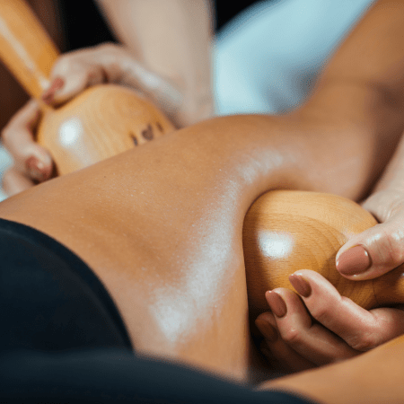 Mujer recibiendo maderoterapia en sus piernas.