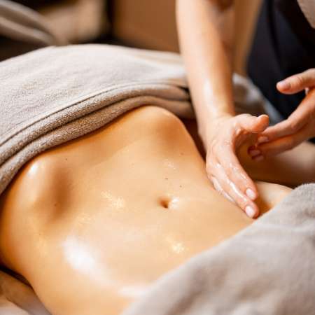 Terapista aplicando un masaje reductor en el abdomen.